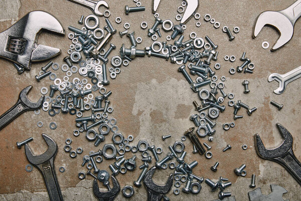 Top view of screws, bolts and wrenches arranged on the background of old  surface