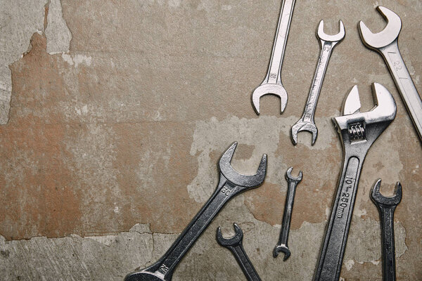 Top view of different wrenches and one monkey wrench on the background of old  surface