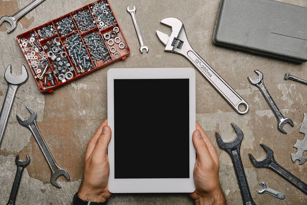 cropped view of laborer using digital tablet on table with different carpentry tools 