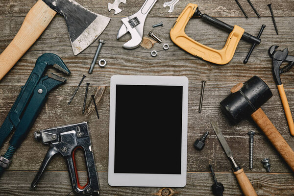 Flat lay with digital tablet and set of carpentry tools on wooden background