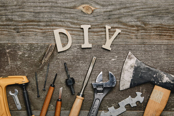 Flay lay with different carpentry tools and diy sign on wooden background