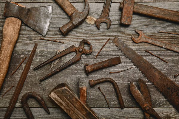 Top view of various rusty carpentry tools on wooden background