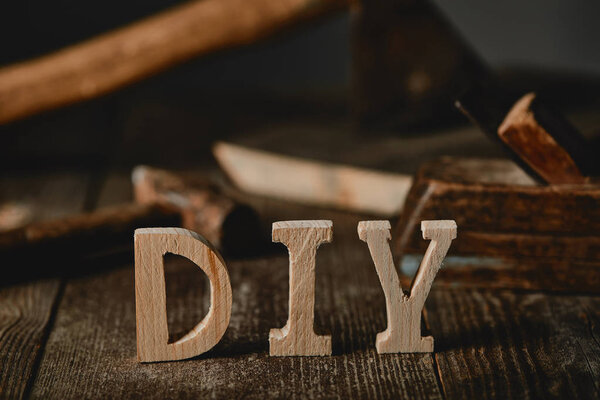 Close up  view of diy sign on wooden table on the background of tools and logs