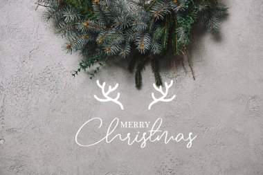 cropped image of fir wreath for Christmas decoration hanging on grey wall with 