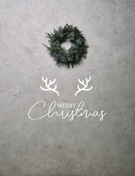 鹿の角で メリー クリスマス のレタリングと灰色の壁に掛かっているクリスマスの装飾のための緑のモミの花輪 — ストック写真
