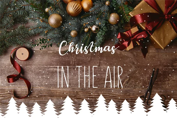 空気のクリスマス インスピレーション 雪とクリスマスの木製テーブルの上クリスマス ギフト用の箱 モミのリース リボン スプールはさみ上から見る木の図 — ストック写真