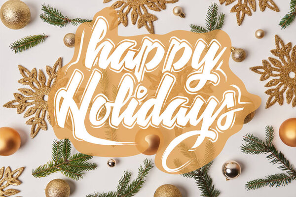 top view of golden Christmas decoration on white with "happy holidays" lettering