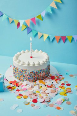 Lezzetli kek şeker sprinkles ve renkli kiraz kuşu ile mavi arka plan üzerine konfeti