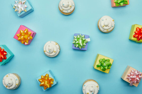 Top view of delicious cupcakes and gifts on blue background