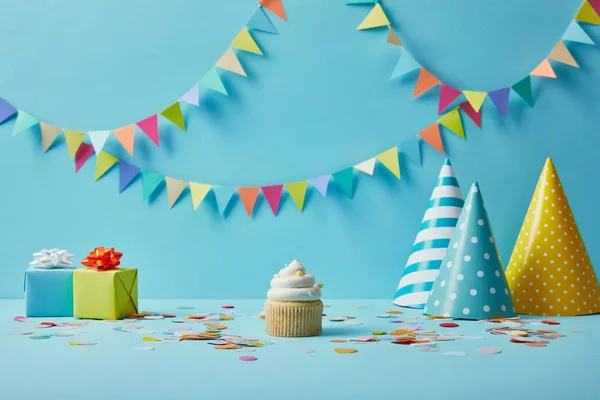 Leckere Cupcake Party Hüte Konfetti Und Geschenke Auf Blauem Hintergrund — Stockfoto