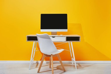 Ahşap masa sandalye sarı duvarının yakınında ile boş ekran ile bilgisayar