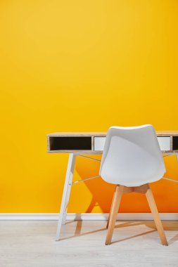 Beyaz sandalye naer sarı duvar ile ahşap masa