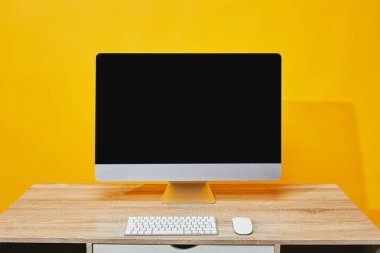 Bilgisayar, klavye ve fare sarı tahta masada çalışma alanı