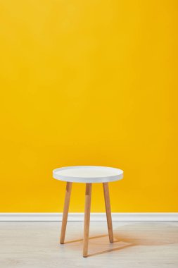 Sarı duvarının yakınında minimalist küçük ahşap masa