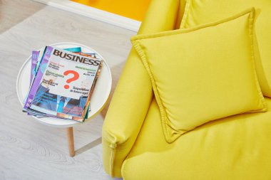 close up of yellow sofa with pillows and coffee table with business magazines clipart
