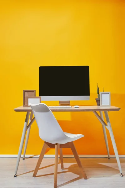 コンピューター フォト フレームや背景に黄色の壁と職場の上にサボテン — ストック写真