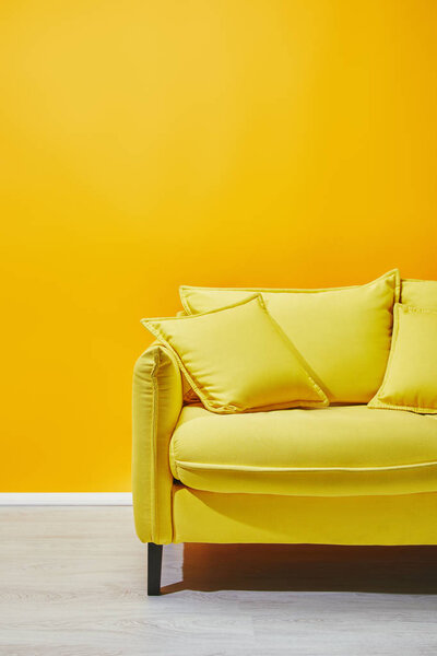 Sofa with pillows near bright yellow wall