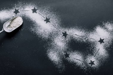 elevated view of scoop on table covered by flour with stars as big dipper constellation 