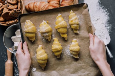 kısmi görünümünü kruvasan hamur tepsiye tablo malzemeler üzerinde tutan kadın 