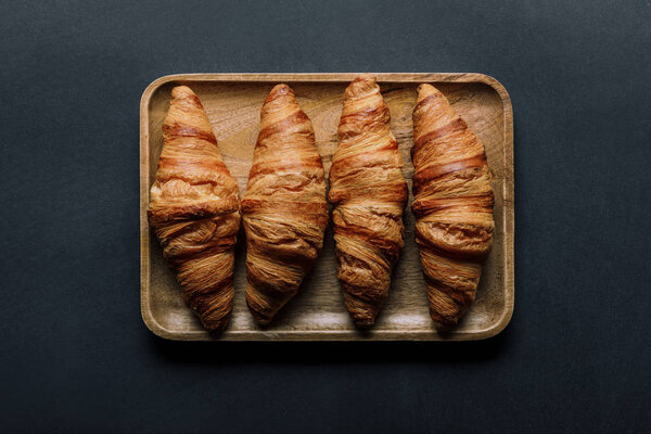 top view of tray with delicious croissants in bowl on black table