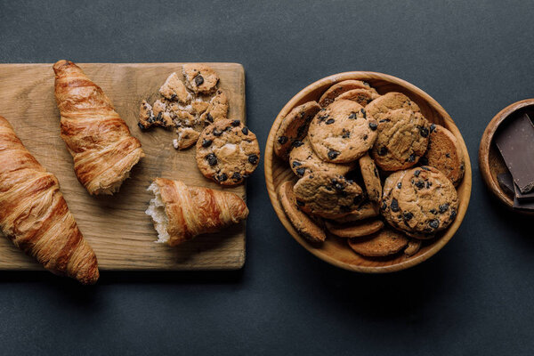 flat lay with arranged croissants, chocolate and cookies on black table