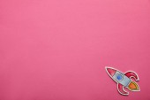 top view of flying rocket on pink background