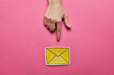 top view of hand pointing at yellow mail sign on pink background clipart