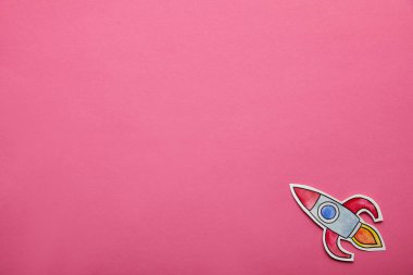 top view of flying rocket on pink background clipart