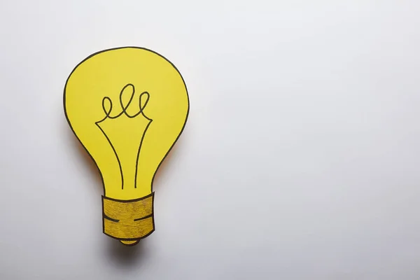 灰色の背景に黄色い電球のアイデアのシンボルのトップ ビュー — ストック写真