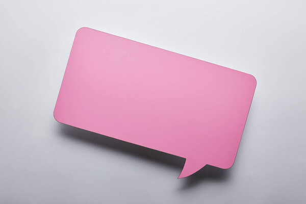 top view of empty pink speech bubble on grey background
