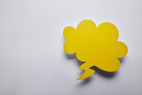 top view of empty yellow thought bubble on grey background