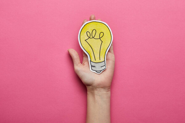 top view of yellow light bulb idea symbol on pink background