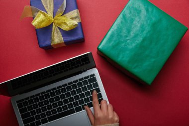 Laptop klavye hediyeler yakınındaki kırmızı zemin üzerine kullanan kadın üstten görünüm 