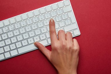 Kırmızı zemin üzerine beyaz bilgisayar klavyesindeki düğmeye kadının üstten görünüm 