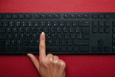 Kadın kırmızı bir arka plan üzerinde siyah bilgisayar klavyesindeki düğmeye görünümünü kırpılmış 