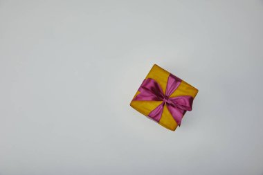 Gri arka plan üzerinde izole mor kurdele ile sarılmış hediye üstten görünüm 