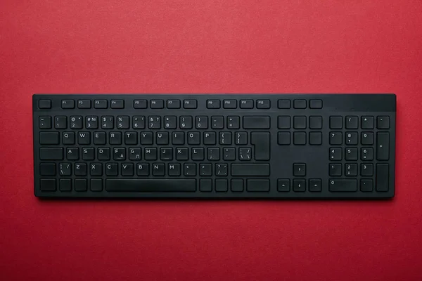 Top view of black plastic computer keyboard on red background