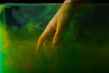 cropped view of man putting hand into water with green paint  clipart