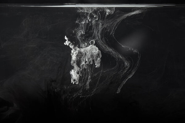 abstract splash of grey acrylic paint on black background