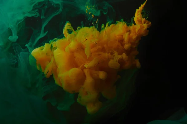 水に塗料の緑とオレンジ色の渦巻きと創造的な背景  — 無料ストックフォト