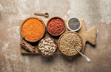 baklagiller, goji meyveleri ve rustik arka plan ile sağlıklı malzemelerle ahşap kurulu üstten görünüm