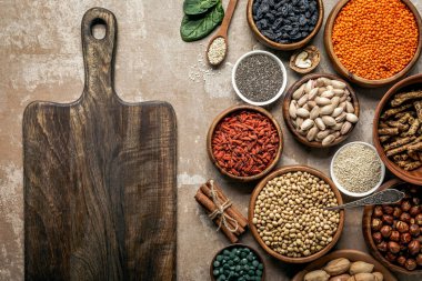 rustik arka plan üzerinde ahşap tahta, superfoods, baklagiller ve sağlıklı malzemelerle üstten görünüm 