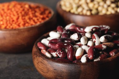 close up of beans in wooden bowl with legumes on background clipart