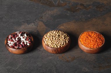 row of beans, lentils and soy in wooden bowls on table clipart