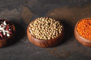 beans, soy and lentils in wooden bowls on table  clipart