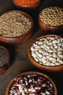 variety of beans with oat groats in wooden bowls on table clipart