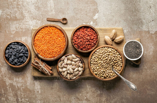 top view of wooden board with legumes, goji berries and healthy ingredients with rustic background