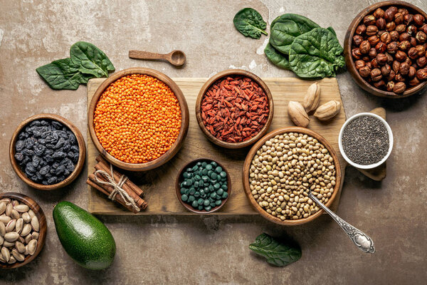 top view of wooden board with legumes, goji berries and healthy ingredients with rustic background