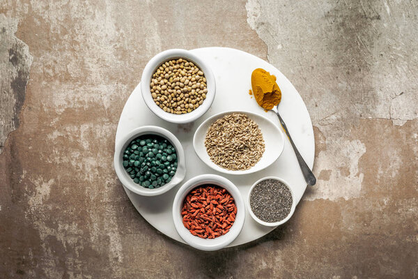 top view of superfoods and legumes on white plate with textured rustic background