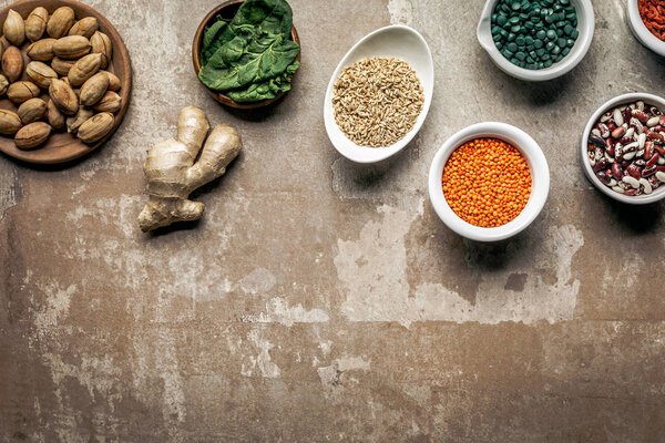 top view of legumes, ginger and spinach on textured rustic background with copy space